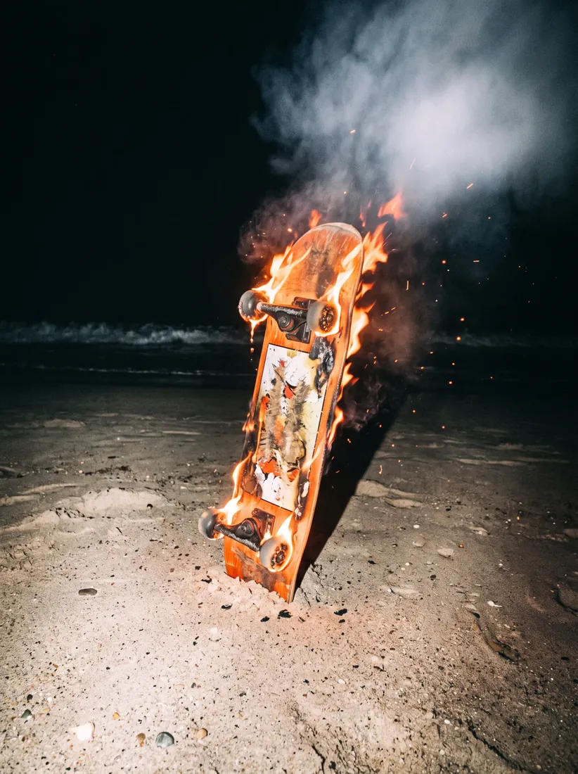 Brennendes Skateboard am Strand